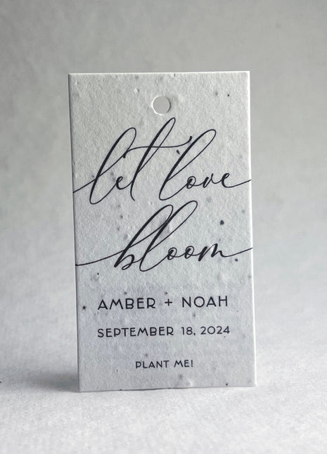Plantable seed paper tag with 'let love bloom' text on a white 
background
