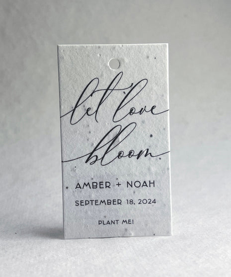 Plantable seed paper tag with 'let love bloom' text on a white 
background